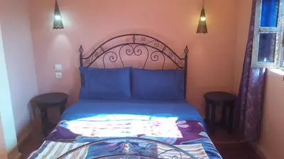 a bedroom with a bed with blue sheets and blue pillows at Riad Tifor in Marrakech