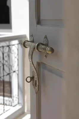 a metal doorhandle on a white door with a window at Riad Utopia Suites And Spa in Marrakech