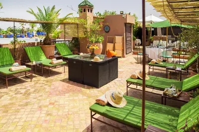 a patio with green benches and a table and chairs at Riad Ayadina & SPA in Marrakech