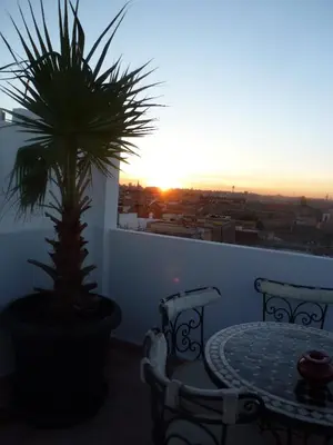 a table and chairs on a balcony with a palm tree at Ryad Laârouss Family in Marrakech