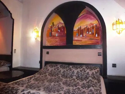 a bedroom with a bed with a painting on the wall at Ryad Laârouss Family in Marrakech
