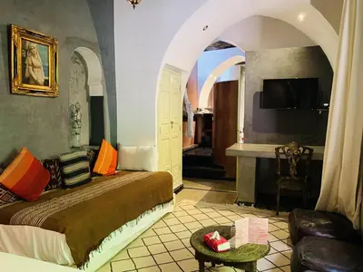 a bedroom with a bed and a living room at Riad Moullaoud in Marrakech