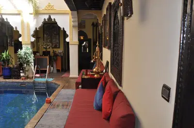 a living room with a couch next to a swimming pool at Riad des Etoiles in Marrakech