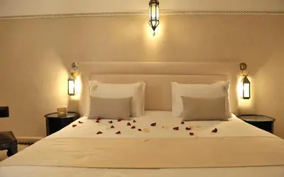 a bedroom with a white bed with roses on it at Riad Le Jardin d'Abdou in Marrakech