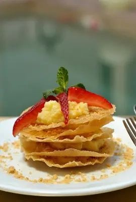 a stack of pancakes with strawberries on top on a plate at Riad Le Jardin d'Abdou in Marrakech