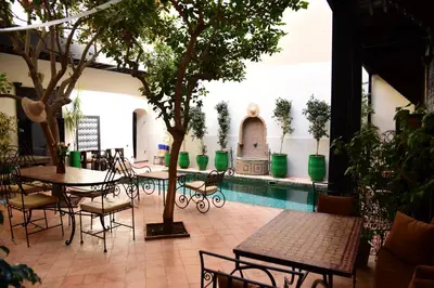 a patio with tables and chairs and a pool at Riad Du Petit Prince in Marrakech