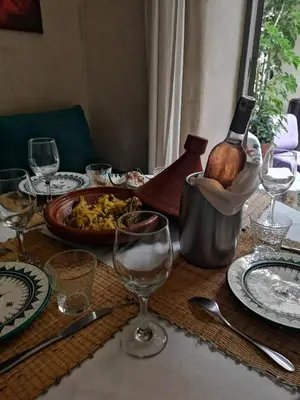 a table with plates and glasses and a bottle of wine at Riad Vendôme & Spa in Marrakech
