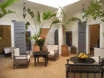 a living room with tables and chairs and plants at Riad Linda in Marrakech