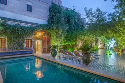 a swimming pool with chairs next to a building at Riad & Spa Laurence Olivier in Marrakech