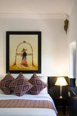 a bedroom with a bed with a painting on the wall at Riad Ajmal in Marrakech