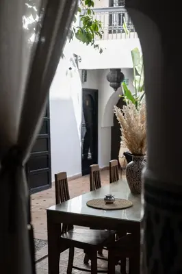 a dining room table with chairs and a vase on it at Riad Ajmal in Marrakech