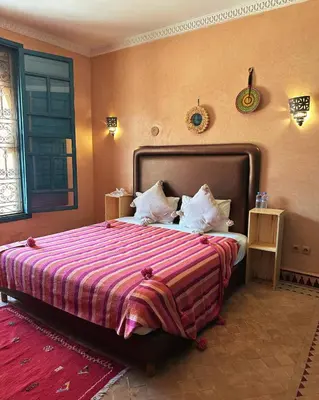 a bedroom with a large bed with a striped blanket at Palais Riad Berbère in Marrakech