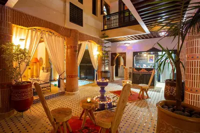 a living room with a table and chairs in a building at Riad Christina in Marrakech