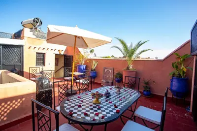 a patio with a table and chairs and an umbrella at Riad Christina in Marrakech