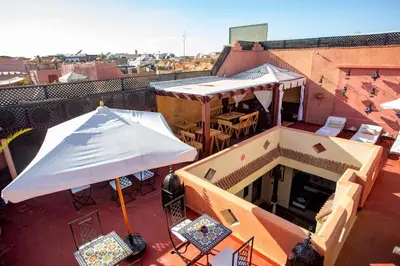 a balcony with an umbrella and tables and chairs at Riad Christina in Marrakech