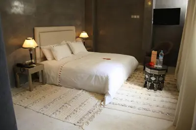a bedroom with a white bed and a table and two lamps at Riad Shama Suites & Spa in Marrakech