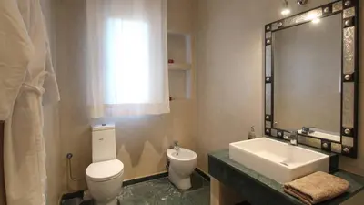 a bathroom with a white toilet and a sink at Palais Ambrine in Marrakech