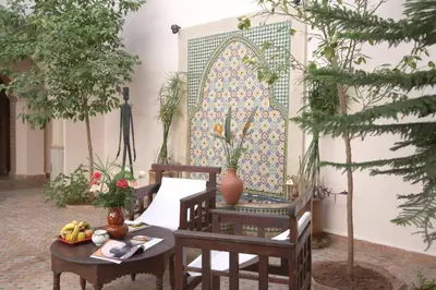 a room with a table and chairs and a wall at Riad Cannelle in Marrakech
