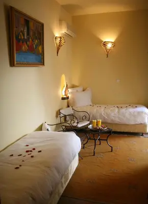 a room with two beds and a table in it at Riad Léna & Spa in Marrakech