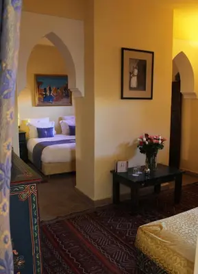 a hotel room with two beds and a table with flowers at Riad Léna & Spa in Marrakech
