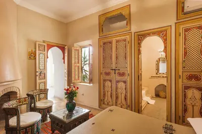 a living room with wooden doors and a table and chairs at Riad Sofia in Marrakech