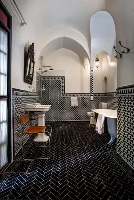 a bathroom with black and white tiles and a tub and sink at Riad Kbour & Chou in Marrakech