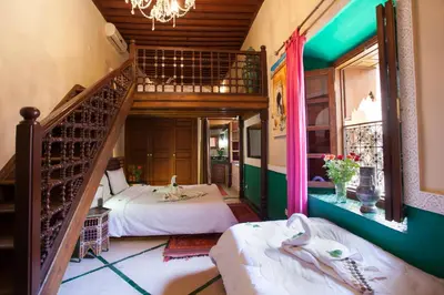 a room with two beds and a spiral staircase at Riad Zanzibar in Marrakech