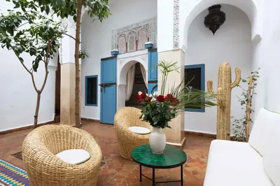 a room with two chairs and a table with a vase of flowers at Riad Assala in Marrakech