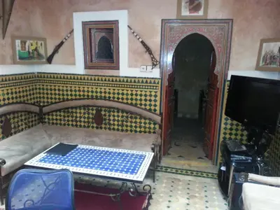 a living room with a table and a tv at Riad Tarik in Marrakech