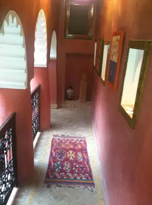 a hallway with a red wall with a rug on the floor at Riad Tarik in Marrakech
