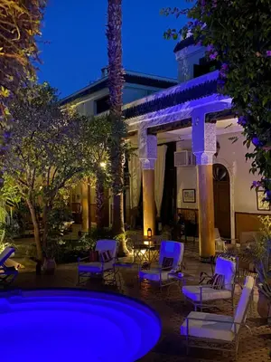 a patio with chairs and a pool at night at Palais El Arsat & Spa in Marrakech