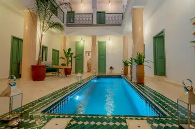 a swimming pool in a large room with a house at Riad Trésor in Marrakech