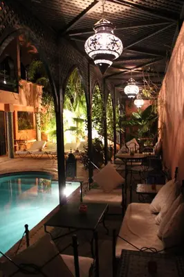 a patio with a pool and chairs and a chandelier at Villa Amira & Spa in Marrakech