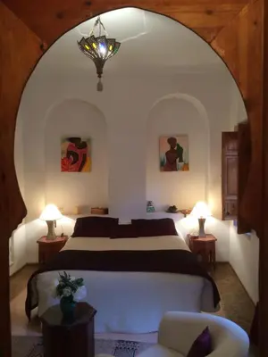 a bedroom with a bed and a chair at Riad Irene in Marrakech