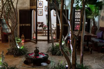 a living room with a fountain in the middle of a room with trees at Riad Houdou in Marrakech