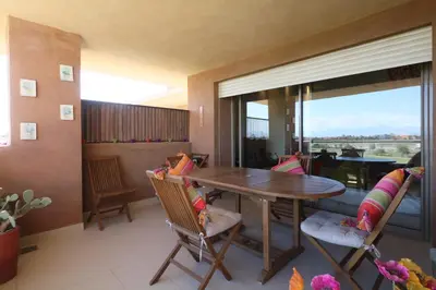 a dining room with a table and chairs and a large window at golf city Av Med VI in Marrakech