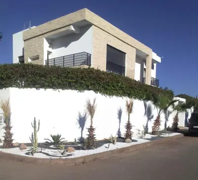 a white house with palm trees in front of it at Villa DAAB OURIDA piscine chauffée Salle de sport in Marrakech