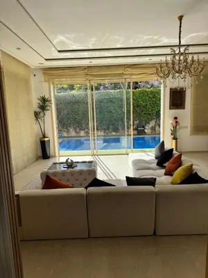 a living room with a white couch and a large window at Villa DAAB OURIDA piscine chauffée Salle de sport in Marrakech