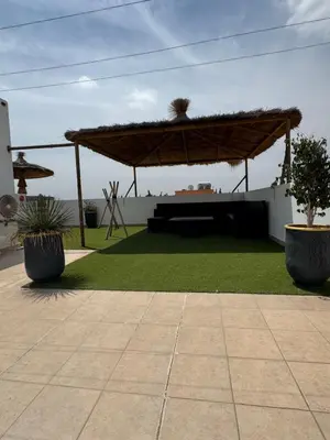 a patio with a large umbrella and grass at Villa DAAB OURIDA piscine chauffée Salle de sport in Marrakech
