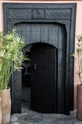 a black door in a fireplace with two plants at Riad Danka in Marrakech