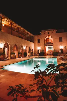 a large swimming pool in a building at night at Caravan Serai in Douar Khalifa Ben Mbarek