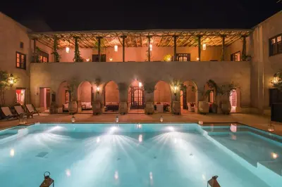 a large swimming pool in a courtyard at night at Caravan Serai in Douar Khalifa Ben Mbarek