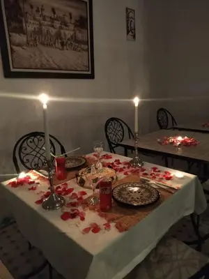 a table with a white table cloth with red flowers on it at Riad El Arco ROOFTOP POOL & Spa in Marrakech