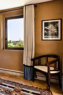 a room with a chair and a window at Villa de Luxe avec Piscine Privée et Golf in Marrakech
