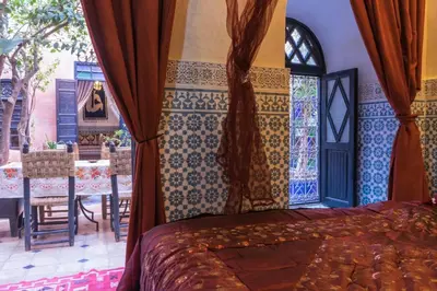a bedroom with a bed and a patio with a table at Riad Sidi Omar in Marrakech