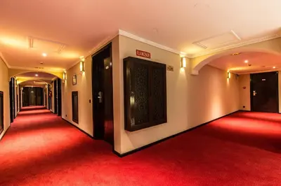 a red carpeted hallway with black doors and a red floor at Hotel Almas in Marrakech