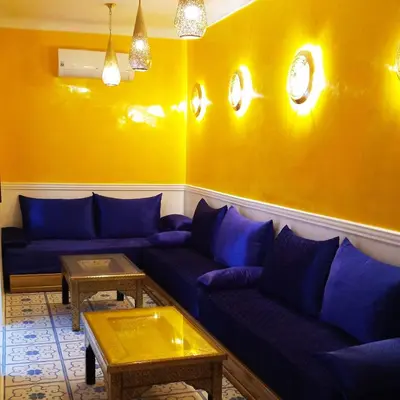 a living room with blue couches and a yellow wall at Riad Heklek in Marrakech