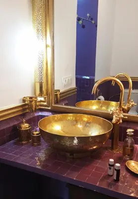 a gold bathroom with two sinks and a mirror at Riad Heklek in Marrakech