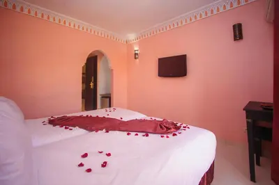 a bedroom with red rose petals on a bed at Hotel El Hadna By HMS in Marrakech