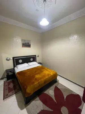 a bedroom with a bed with a yellow blanket on it at Hôtel Narjisse in Marrakech